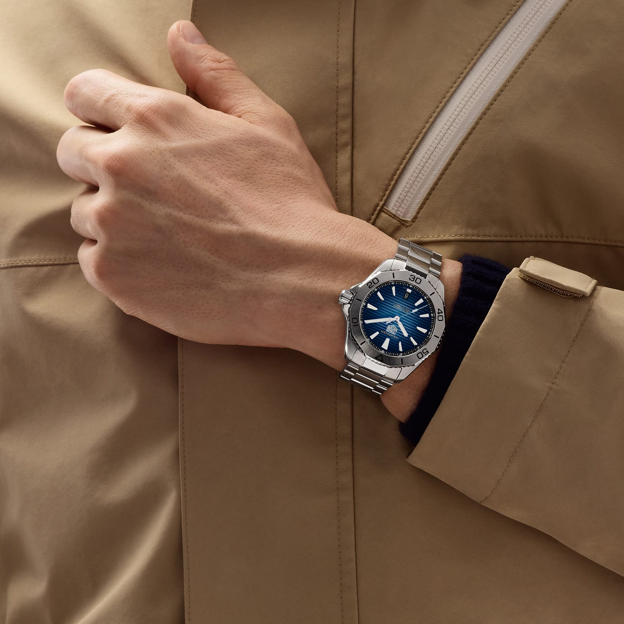 TAG Heuer Aquaracer Professional 200 Date WBP2111.BA0627 shown worn on the wrist, illustrating the case proportions and steel bracelet fit. The blue dial stands out against the sleeve in frame.