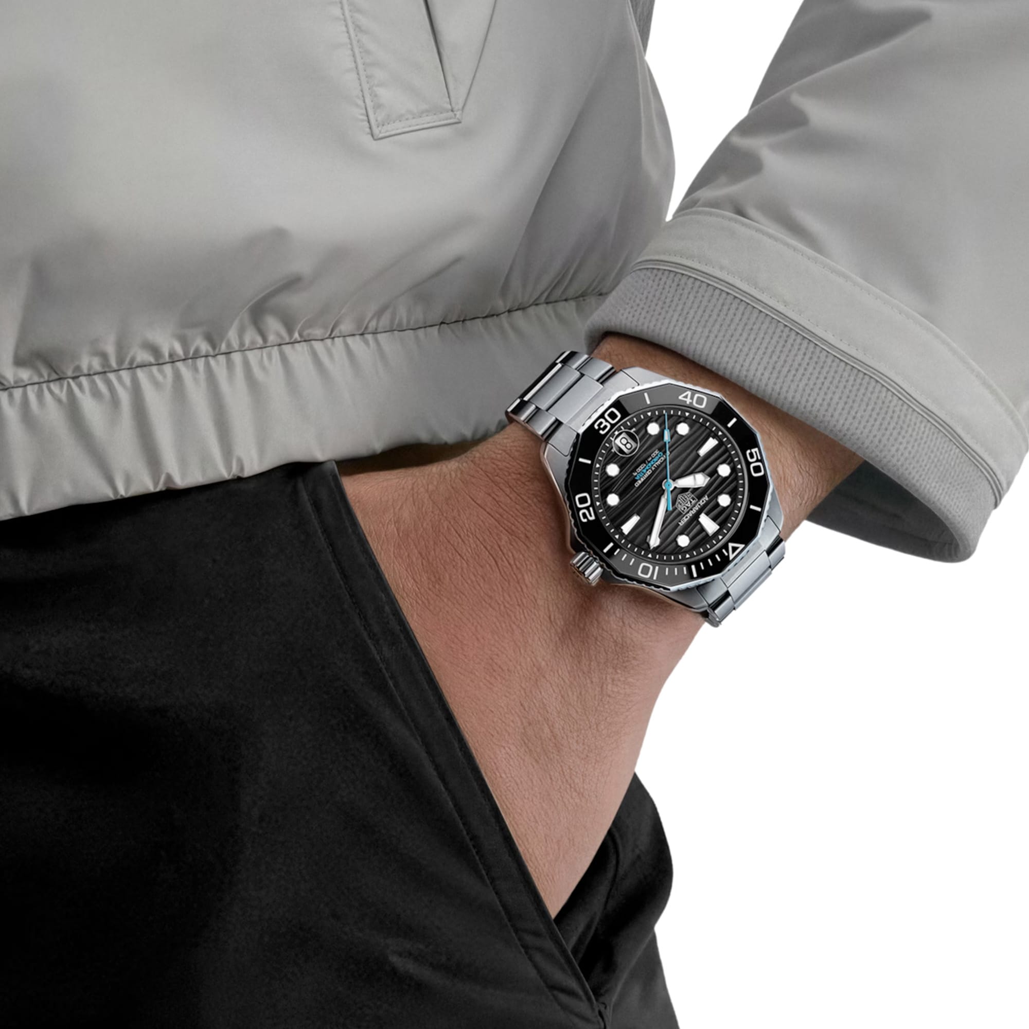 TAG Heuer Aquaracer Professional 300 Date WBP5110.BA0013 shown worn on the wrist, illustrating the case proportions and steel bracelet fit. The black dial stands out against the dark jacket sleeve in frame.