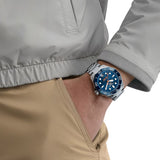 TAG Heuer Aquaracer Professional 300 Date WBP5111.BA0013 shown worn on the wrist, illustrating the case proportions and steel bracelet fit. The blue dial stands out against the tan jacket sleeve in frame.