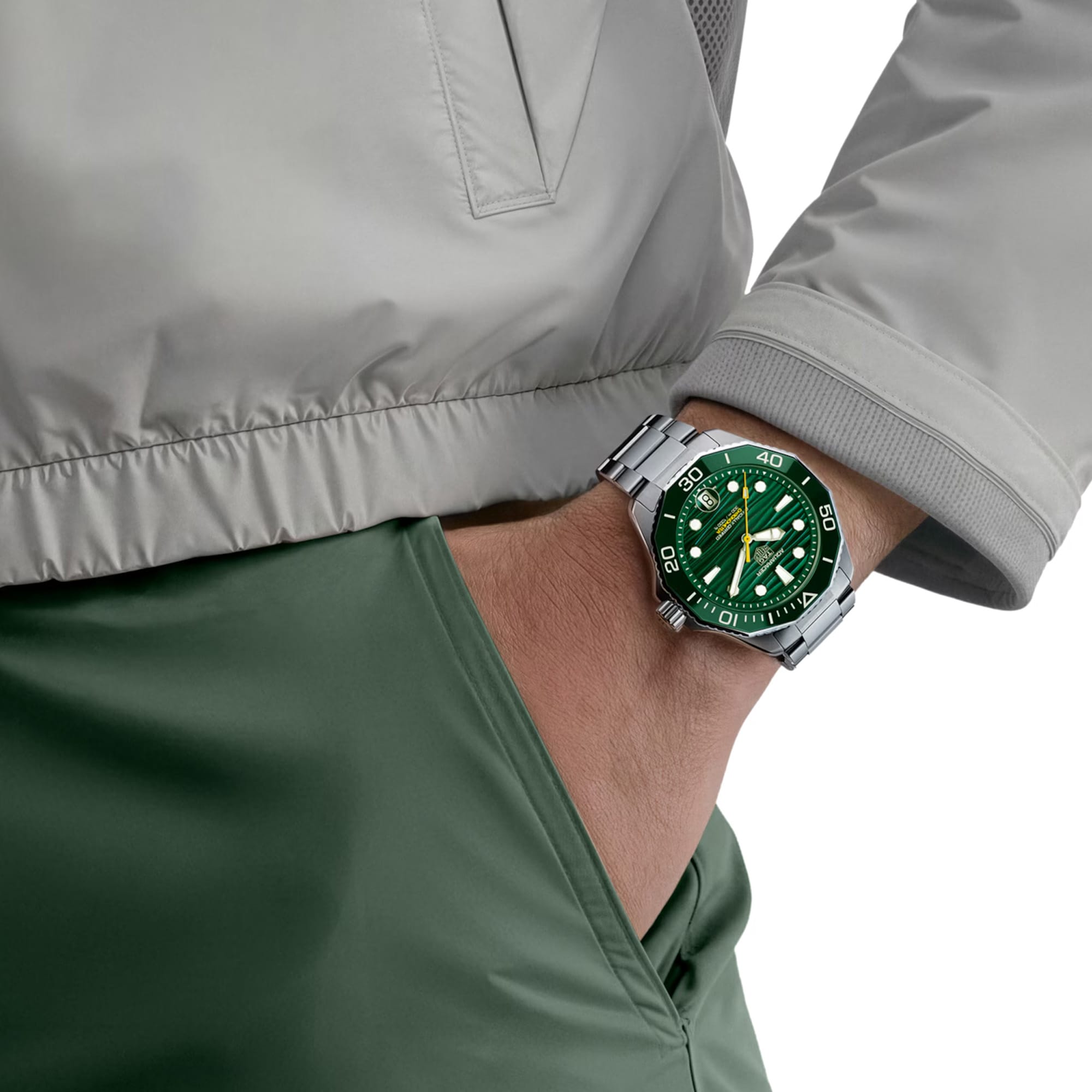 TAG Heuer Aquaracer Professional 300 Date WBP5116.BA0013 shown worn on the wrist, illustrating the case proportions and steel bracelet fit. The green dial stands out against the grey jacket sleeve in frame.