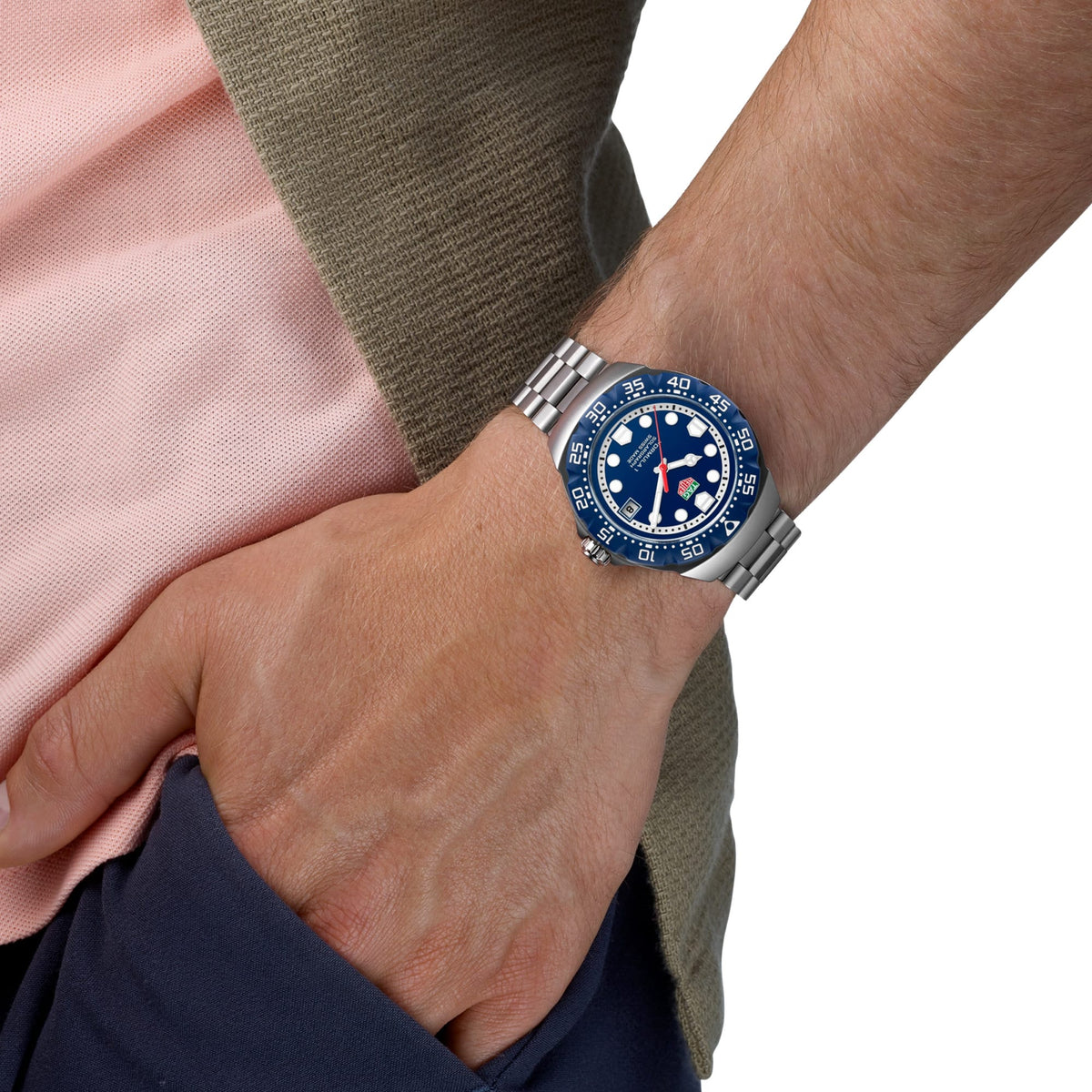 TAG Heuer Formula 1 Solargraph WBY1112.BA0042 shown worn on the wrist, illustrating the case proportions and steel bracelet fit. The blue dial stands out against the pink sleeve in frame.