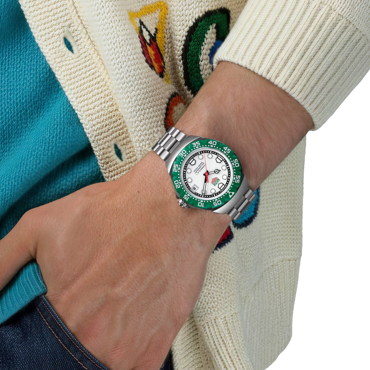TAG Heuer Formula 1 Solargraph WBY111E.BA0042 shown worn on the wrist, illustrating the case proportions and steel bracelet fit. The white dial and green bezel stand out against the colourful sleeve in frame.