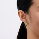 On-body view of a model wearing the Wallace Bishop Opal Starburst Huggies in 9ct Yellow Gold, hugging the earlobe with a 2.5mm round white opal on each earring.