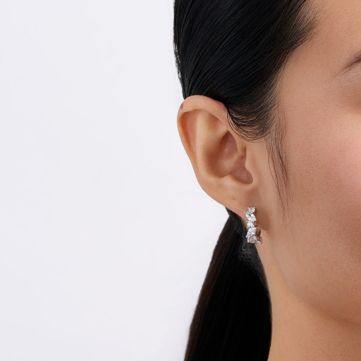 On-body view of a model wearing the Wallace Bishop Cubic Zirconia Cluster Huggies in Sterling Silver, 15mm in length, hugging the earlobe with a scatter of colourless cubic zirconias.