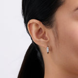 On-body view of a model wearing the Wallace Bishop Cubic Zirconia Scatter Huggies in Sterling Silver, 15mm in size, hugging the earlobe with a scatter of white cubic zirconias in mixed cuts.