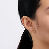 On-body view of a model wearing the Wallace Bishop Swiss Blue Topaz Bezel Stud Earrings in 9ct Yellow Gold, with a 3mm round Swiss blue topaz in each earlobe.
