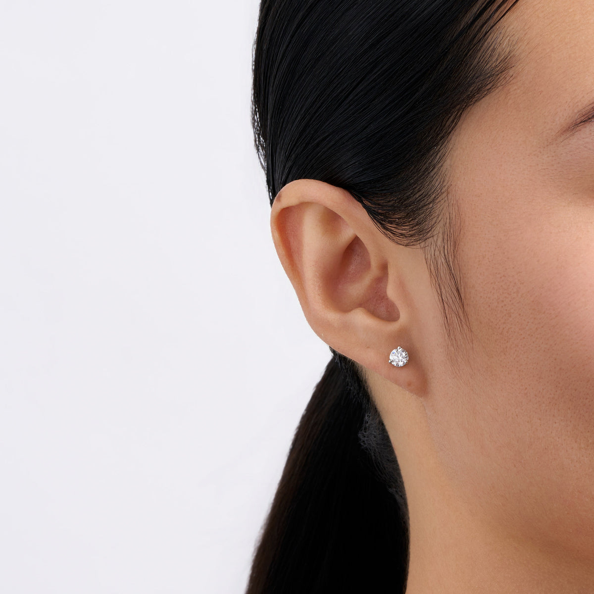 On-body view of a model wearing the Wallace Bishop 1.00 TDW Round Lab-Grown Diamond Solitaire Stud Earrings in Sterling Silver, with a three-claw set round lab-grown diamond in each earlobe.