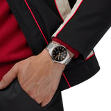 TAG Heuer Carrera Day-Date WDA2111.BA0043 shown worn on the wrist, illustrating the case proportions and steel bracelet fit. The black dial and rose gold accents stand out against the dark jacket sleeve in frame.