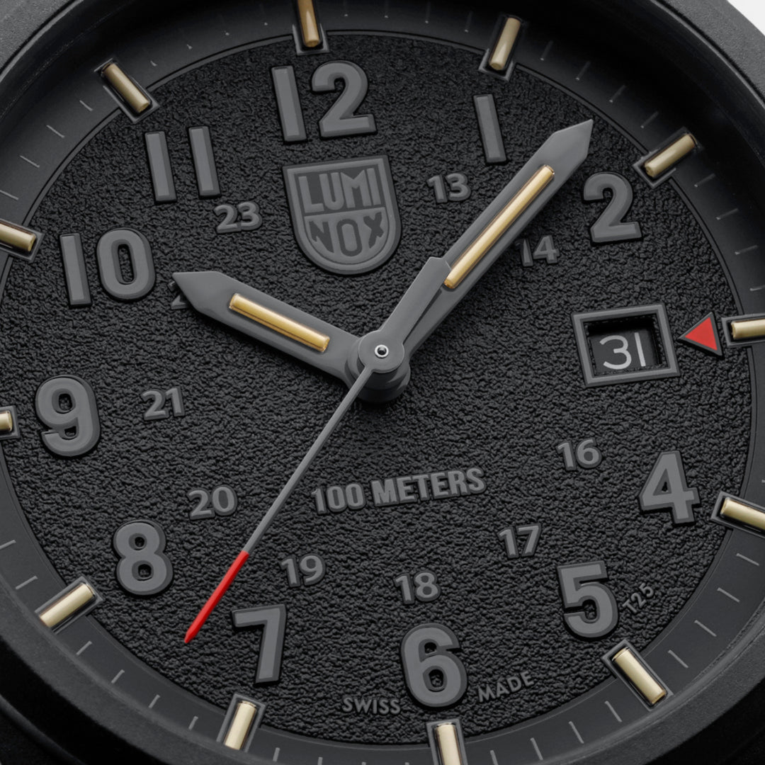 Close-up of the textured black dial on the Luminox Atacama Field Men's 43mm Quartz Watch XL.1961, showing the 12 and 24-hour numerals, red-tipped seconds hand and red arrow beside the date at 3 o'clock. This Atacama Field watch features self-powered tritium tubes for constant visibility in the dark.