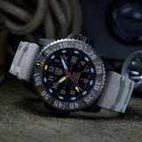 Luminox MIL-SPEC Men's 46mm Quartz Watch XL.3359.SET shown in a rugged outdoor setting. This MIL-SPEC 3350 Series military watch features a black dial, a titanium bezel, a white strap and 300m water resistance.