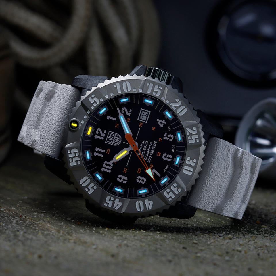 Luminox MIL-SPEC Men's 46mm Quartz Watch XL.3359.SET shown in a rugged outdoor setting. This MIL-SPEC 3350 Series military watch features a black dial, a titanium bezel, a white strap and 300m water resistance.