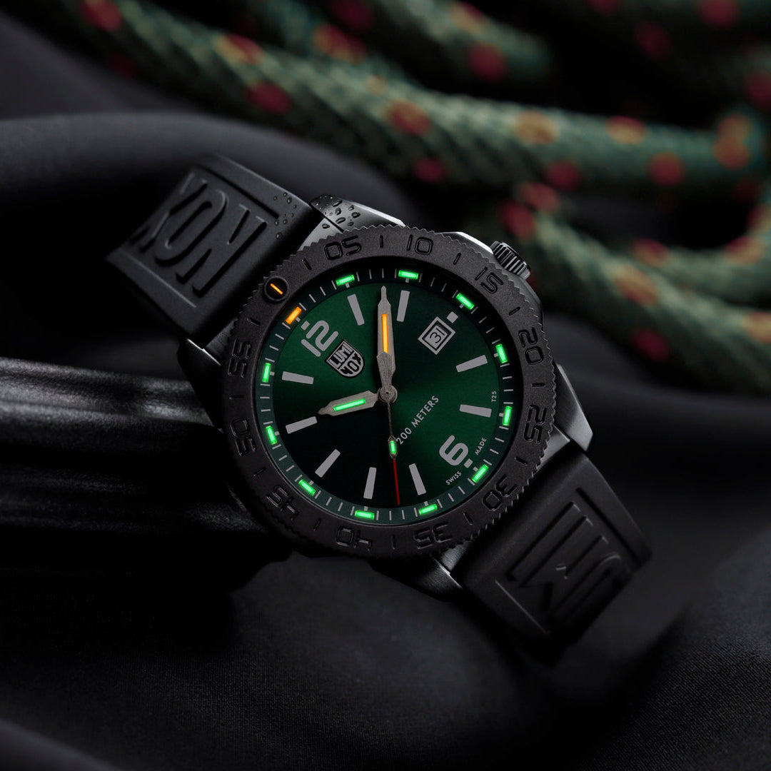 Luminox Pacific Diver Men's 44mm Quartz Watch XS.3137.B shown in a coastal outdoor setting. This Pacific Diver 3120 Series dive watch features an emerald green sunray dial, a black IP stainless steel case and 200m water resistance.