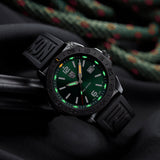 Luminox Pacific Diver Men's 44mm Quartz Watch XS.3137.B shown in a coastal outdoor setting. This Pacific Diver 3120 Series dive watch features an emerald green sunray dial, a black IP stainless steel case and 200m water resistance.