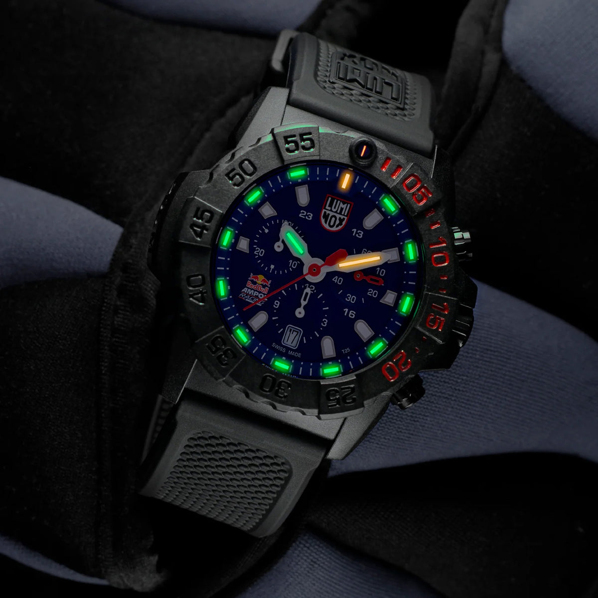 Luminox Navy SEAL Red Bull Ampol Racing Edition Men's 43mm Quartz Chronograph Watch XS.3581.EY.ARB shown in a motorsport-inspired setting. This limited edition chronograph features Red Bull Ampol Racing branding, a lightweight CARBONOX™ case and 200m water resistance.