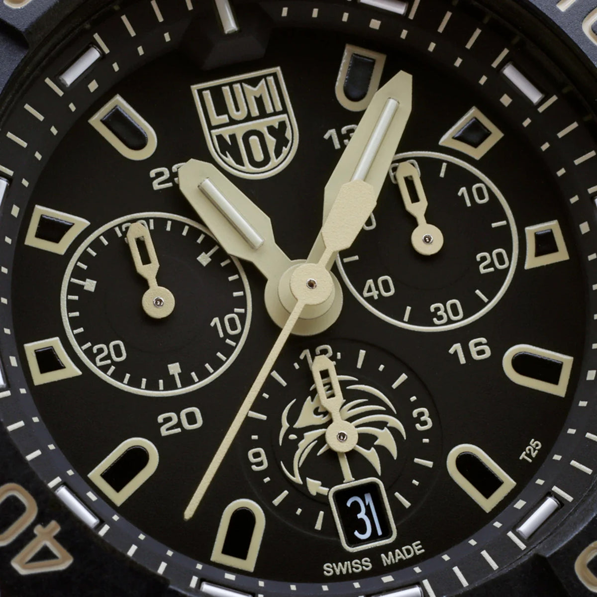 Close-up of the black dial on the Luminox Navy SEAL Foundation Men's 45mm Quartz Chronograph Watch XS.3590.NSF.SET, showing the sand-coloured details, three chronograph sub-dials and the Navy SEAL Foundation logo at 6 o'clock. This Navy SEAL Foundation Chronograph features luminous hands and markers with self-powered tritium tubes.