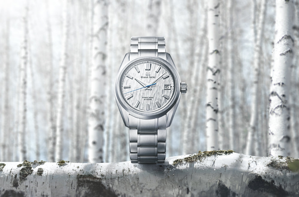 Grand Seiko watch on a branch with a snowy forest background