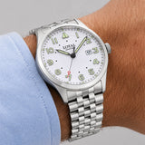 The Loyal Adventurer Pilot Watch worn on the wrist, showing the true scale of the 40mm case and white dial. The stainless steel finish and 12 o'clock orientation triangle give this quartz watch a distinctive, versatile look for daily wear, alongside the bonus brown leather strap included with this set.