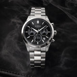 The Loyal Academy Steel Chronograph Watch features a black dial with chronograph sub-dials, framed by a stainless steel case, reference 03R85MBZ1. This 40mm quartz watch pairs a stainless steel bracelet with a mineral glass lens and 100m water resistance.
