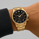 The Loyal Academy Gold PVD Men's Chronograph Watch worn on the wrist, showing the true scale of the 40mm case and black chronograph dial. The Gold PVD finish and gold-tone bracelet give this quartz watch a bold, versatile look for daily wear.