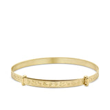 A children’s expanding bangle shown front on in 9ct yellow gold, with a round shape and classic toys embossed around the surface. 40mm in size.