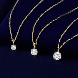 Flat lay view of three Wallace Bishop Essence Round Diamond Solitaire Pendants in 9ct Yellow Gold, each on a cable chain with a parrot clasp: the 0.07 TDW pendant, reference 3PBRI008Y, measuring 10mm in length, the 0.23 TDW pendant, reference 3PBRI023Y, and the 0.50 TDW pendant, reference 3PBRI05Y, measuring 11.30mm in length. Each pendant features a single natural round diamond in an illusion setting, hanging from a bale.