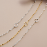 Flat lay view of three Wallace Bishop charm holder chains, each 500mm (approximately 19.7 inches) in length and 2.8mm in width, with a parrot clasp: the Paperclip Charm Holder Chain in Sterling Silver, reference 44PCCH01, the Trombone Link Charm Holder Chain in Sterling Silver, reference 44TBCH01, with a round ring for charms and pendants, and the Paperclip Charm Holder Chain in 9ct Yellow Gold, reference 46PCCH01Y.