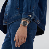 TAG Heuer Formula 1 Chronograph CAZ1010.BA0842 shown worn on the wrist, illustrating the case proportions and steel bracelet fit. The black dial stands out against the denim jacket sleeve in frame.