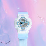 Casio Baby-G BA110PD-2A women's watch front view, featuring a 43.4mm round resin case with a polarised blue and white finish across the bezel and multi-layered dial, metallic heart-shaped accent at the 3 o'clock position, analogue hands, and three digital display windows.