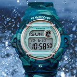 Lifestyle shot of the Casio BABY-G BG169CM-2D Digital Women's Watch styled in an everyday casual setting. The teal camouflage print and translucent dial are shown in a natural, real-world context.