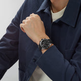 TAG Heuer Formula 1 Chronograph CAZ1010.FT8024 shown worn on the wrist, illustrating the case proportions and black rubber strap fit. The black dial stands out against the sleeve in frame.