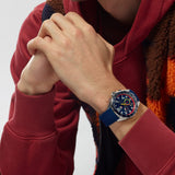 TAG Heuer Formula 1 Chronograph x Red Bull Racing CAZ101AL.FT8052 shown worn on the wrist, illustrating the case proportions and blue rubber strap fit. The blue dial and red accents stand out against the sleeve in frame.