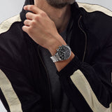 TAG Heuer Carrera Chronograph CBN2A1B.BA0643 shown worn on the wrist, illustrating the case proportions and steel bracelet fit. The black dial stands out against the sleeve in frame.
