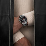 TAG Heuer Carrera Chronograph CBS2114.BA0053 shown worn on the wrist, illustrating the case proportions and steel bracelet fit. The black dial stands out against the sleeve in frame.
