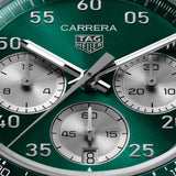 TAG Heuer Carrera Chronograph Sport CDB2112.BA0054 captured in extreme close-up on the teal green sunray-brushed dial, highlighting the grey-lacquered chronograph hands and silver numerals. The Super-LumiNova-treated hands sit against the teal green dial surface.