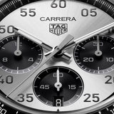 TAG Heuer Carrera Chronograph Sport CDB2113.BA0054 captured in extreme close-up on the silver sunray-brushed dial, highlighting the grey-lacquered chronograph hands and black numerals. The Super-LumiNova-treated hands sit against the silver dial surface.