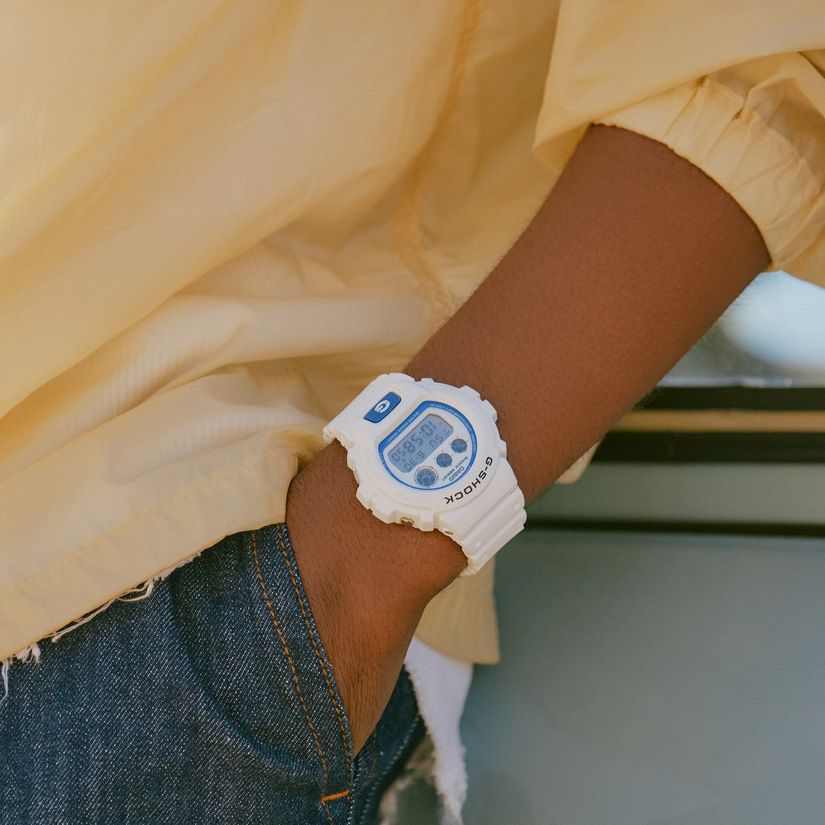 The Casio G-SHOCK Quartz Men's Watch DW-6900HDS-7 worn on the wrist to show scale and fit. The white resin case and band with blue accents suit everyday casual wear.