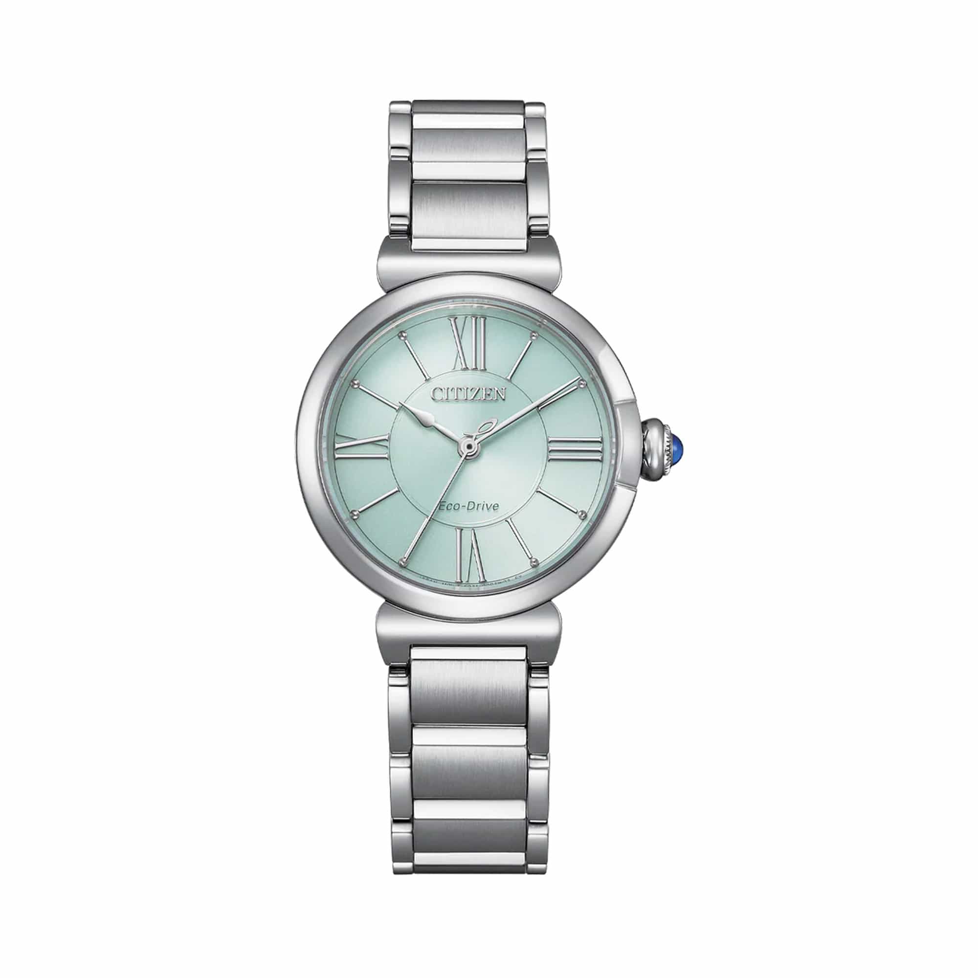 Close-up of the Citizen L May Bells EM1070-83L face, showing the pale green dial with Roman numeral and baton markers and blue cabochon crown. The stainless steel case and sapphire crystal are visible.