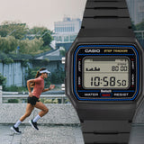 Lifestyle shot of the Casio Vintage Digital Watch F-B100W-1A styled in an active, everyday setting, reflecting its Bluetooth step-tracking function. The black resin case and blue dial accent are shown in a natural, real-world context.