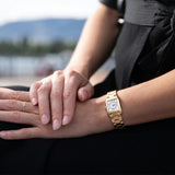 Frederique Constant Carrée Quartz Women's Watch FC-200MCDC25B worn on the wrist, demonstrating the fit of its rectangular case and gold-tone bracelet with push-button fold-over clasp. The diamond bezel adds sparkle and dimension on the wrist.