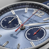 Close-up of a Healey Frederique Constant watch dial with a light blue textured finish, silver-tone indices, two dark blue subdials, and red seconds hands.