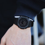 Casio G-Shock GA-2100-1A1 watch front view, featuring a 45.4mm all-black octagonal resin case with Carbon Core Guard construction, clean monochromatic analogue-digital dial with Arabic numeral indices, inverted LCD display, and distinctive integrated band design.