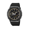 The Casio G-Shock Analogue Digital Men's Watch GM2100LXB-1A9 features a deep matte black anti-reflective textured dial with gold vapour-deposited hour markers, gold-edged slim extended hands, gold decorative frame around the glass, and gold G-Shock logo, set within a 49.3mm octagonal black ion-plated stainless steel bezel.