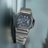 Three-quarter angle view of the Casio G-SHOCK 2500 Series Quartz Men’s Watch GMC2500D-1A2, 46.7mm case, highlighting the silver bezel and rounded octagonal case. The blue dial and bar indexes are visible.