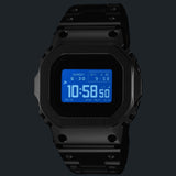 The Casio G-Shock Digital Watch GMWBZ5000BD-1D photographed in low light with the Super Illuminator LED backlight activated, showing the all-black ion-plated full-metal case glowing with bright LED illumination across the MIP LCD display — outstanding night-time readability in a dramatic all-black form.