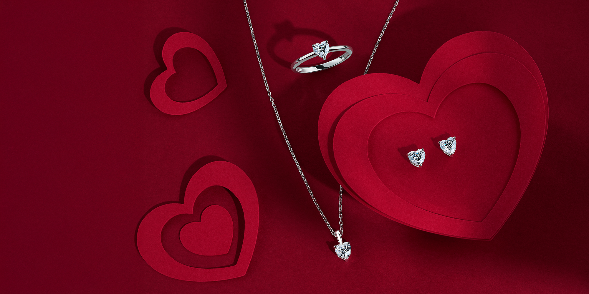 Silver jewelry set with heart-shaped box on a red background