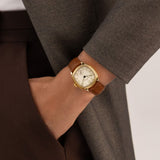 Hamilton American Classic Cushion Mechanical Women’s 30mm Watch H36119520 is worn on the wrist with its brown leather strap fastened. The compact 30mm case and beige dial suit a classic dress watch look.
