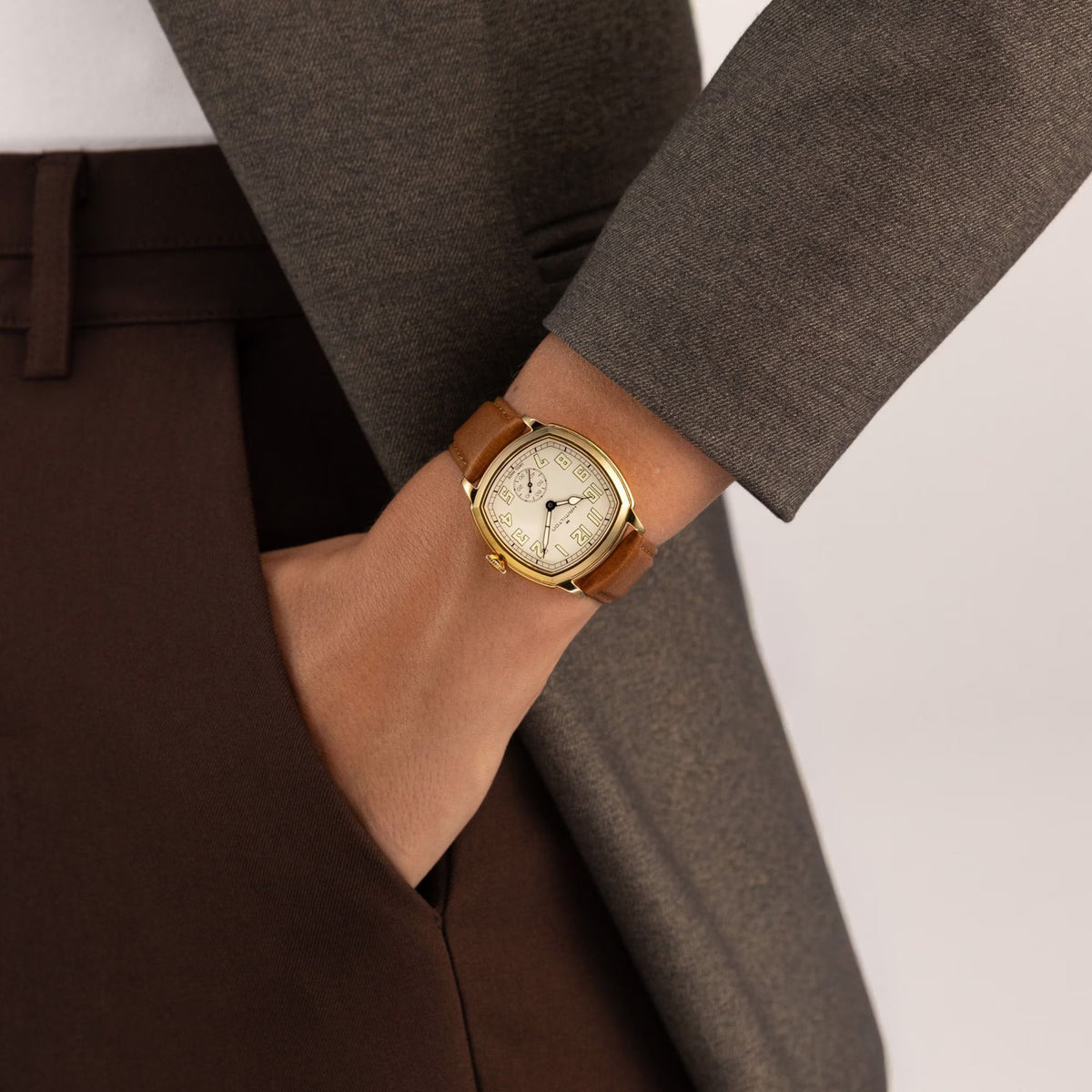 Hamilton American Classic Cushion Mechanical Unisex 34mm Watch H36139520 is worn on the wrist with its brown leather strap fastened. The square case and beige dial suit a classic dress watch look.