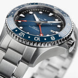 Hamilton Khaki Navy Scuba Auto GMT 43mm Watch H82535140 is shown at a 3/4 angle, highlighting the sapphire crystal, blue dial, and ceramic GMT bezel together. The angle showcases the watch's travel-ready, diving-inspired design.