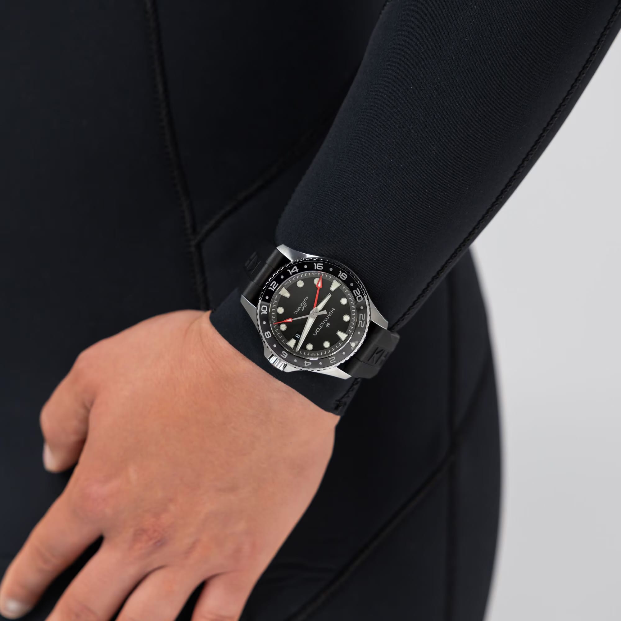 Hamilton Khaki Navy Scuba Auto GMT 43mm Watch H82555330 is paired with a sporty black rubber strap secured by a pin buckle. Its 43mm case delivers a robust, travel-ready presence suited to adventurers on the move.