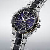 A Seiko Autumn chronograph watch with a silver stainless steel link bracelet, black inlay segments, and a purple sunburst dial with black subdials and a gold-tone bezel.